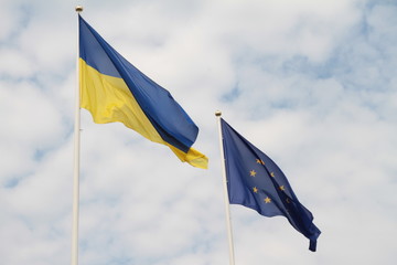 Flags of European Union and Ukraine waving on flagpoles isolated on white background