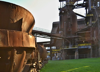 Old rusty cup for casting steel on a green field in an abandoned steelworks factory