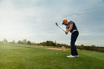 Fototapeta premium Golfer hitting iron club on golf course on fairway. Golf ball on tee.
