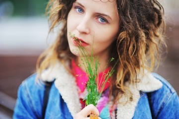 Young pretty girl with dreads with a bouquet of herbs in hand on a blurred background, closeup.