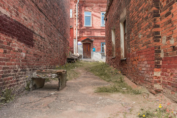 An old neglected quarter, walls of red brick destroyed form a perspective to the front door of a residential building