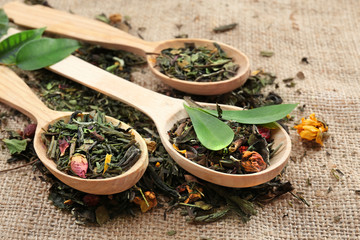 Dried tea in wooden spoons on sackcloth