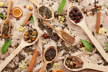Dried tea in wooden spoons on paper background