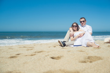 Fototapeta premium Young romantic couple sitting on the beach