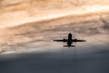 A commercial airplane during takeoff from the airport. Silhouette flying over sky at sunset or sunrise background,