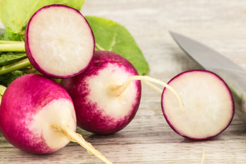 Juicy fresh radish in a cut on a white wooden background close up.