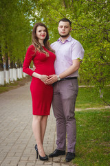 Happy young couple expecting baby in summer park