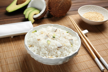 Bowl with coconut rice on bamboo mat