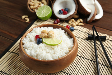 Coconut rice with berries, cashew nuts and lime slice on bamboo mat