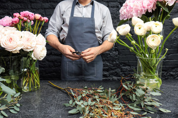 Male florist creating beautiful bouquet in flower shop, close up