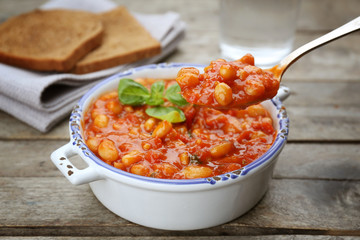 Spoon of delicious Italian butter beans and pan on background