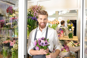 Young handsome florist with beautiful bouquet at flower shop