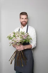 Crédence de cuisine en verre imprimé Fleuriste Young handsome florist with beautiful bouquet on grey background