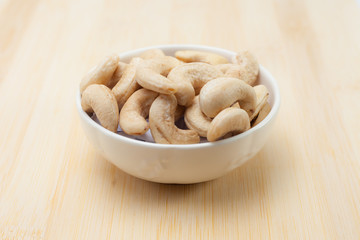 cashew nut in a white bowl on wooden background
