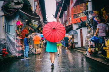 Deurstickers Shanghai Mensenvrouw die in de winkelstraat van Chinatown loopt Regenachtige dag meisje toerist onder rode oosterse paraplu in smalle steegjes op China reizen in Shanghai.