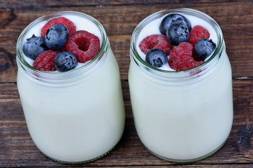 Assorted berries with yogurt in a jars glass on table