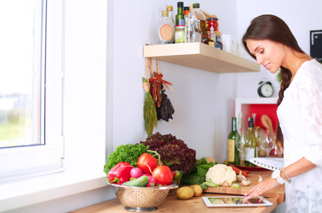 Young woman using a tablet computer to cook in her kitchen