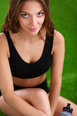 Woman sitting with crossed legs on the green grass