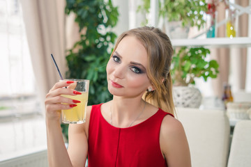 Young businesswoman having break in cafe and drinking lemonade. She is looking at the camera.