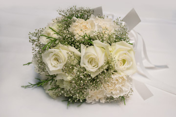Bridal bouquet of white rose on white fabric background