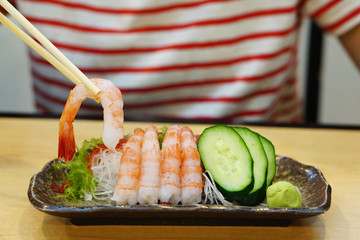 Fresh Amaebi (Sweet Shrimp) Sashimi Set served with wasabi, zucchini seaweed and grated radish on plate.