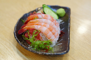Fresh Amaebi (Sweet Shrimp) Sashimi Set served with wasabi, zucchini seaweed and grated radish on plate.