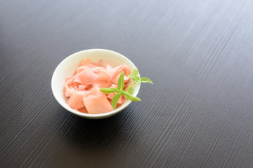 A small dish of picked pink ginger isolated on black background.