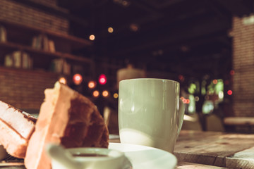 2 pieces of waffle with a white cup of coffee on the wooden table