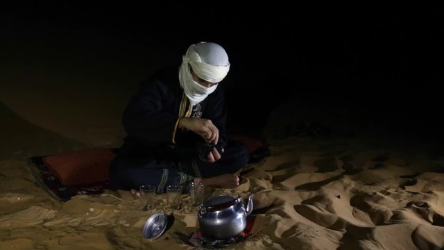 Tuareg man making tea in a desert at night