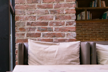 the leather sofa and pillow with red brick background in the coffee shop