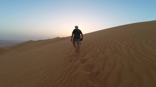 Man walking up sand dunes of Liwa desert