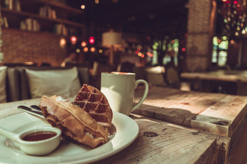 2 pieces of waffle with a white cup of coffee on the wooden table