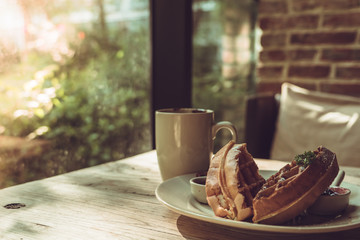 2 pieces of waffle with a white cup of coffee on the wooden table