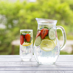 Dietary detox drink with lemon juice, red strawberry, cucumber and mint leaves in clear water with...