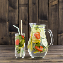 Dietary detox drink with lemon juice, red strawberry, cucumber and mint leaves in clear water with ice.