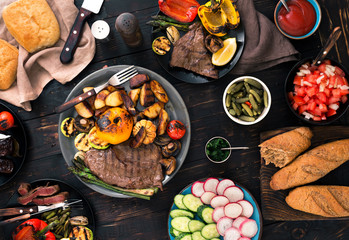  grilled steak and grilled vegetables on dark wooden table
