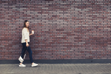 Fototapeta na wymiar Trendy Women Walking At The Brick Wall Background