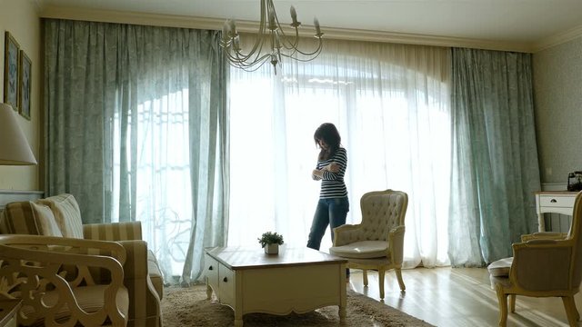 Upset woman going forth and back along the window of a cozy apartment