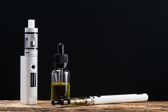 Electronic cigarette and a bottle with aroma, concept on a wooden board