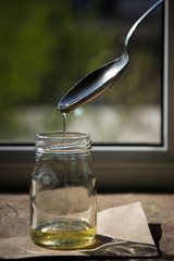 Organic pure honey in jar on window sill. Stream of honey
