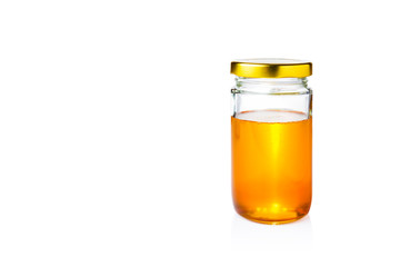 golden honey in glass jar with lid on white background