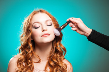 Obraz premium Master inflicts brush powder on the face of the girl