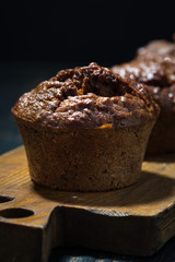 chocolate muffins on a wooden board, vertical closeup