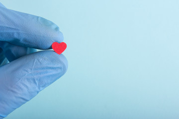 A new life in the hand of a doctor. A gloved hand hold hearts.