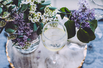 lilac flowers and white wine on marble background
