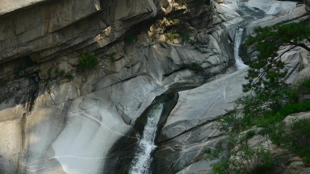 Mountain waterfall stream into pool from multilayer stone,forests & shrubs.