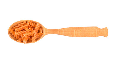 Carrot pasta fusilli in a wooden spoon on a white background, top view
