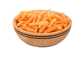 Uncooked pasta fusilli in a wooden bowl on a white background