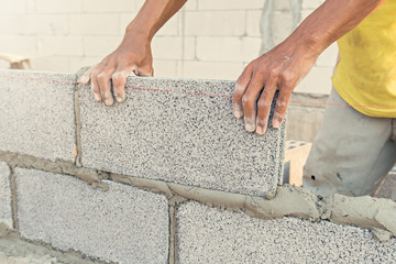 Close up of industrial bricklayer installing bricks on construction site