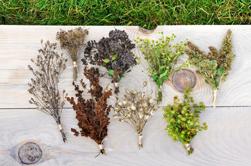 Fototapeta premium Various dried herbs collected in bunches on a light wood surface. Top view.